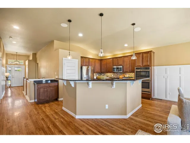 a living room with stainless steel appliances kitchen island granite countertop a refrigerator a stove top oven a sink and a center island