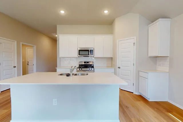 a kitchen with stainless steel appliances a refrigerator sink and white cabinets