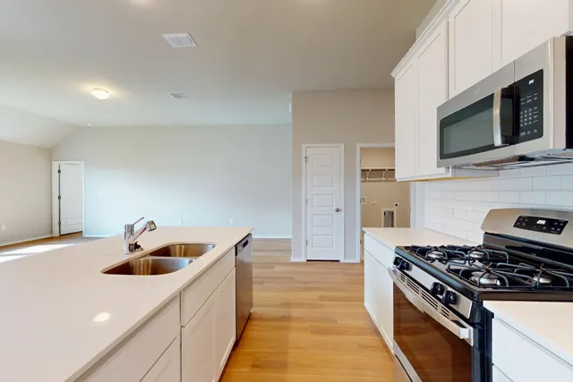 a kitchen with stainless steel appliances a sink a stove and a microwave