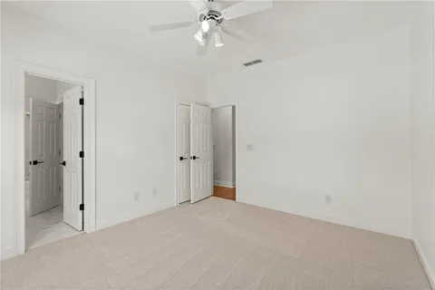 an empty room with windows and ceiling fan
