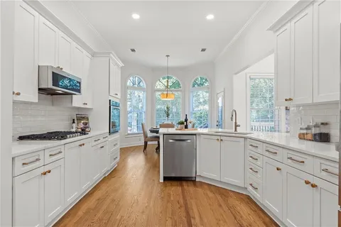 a large kitchen with a lot of counter space and wooden floor