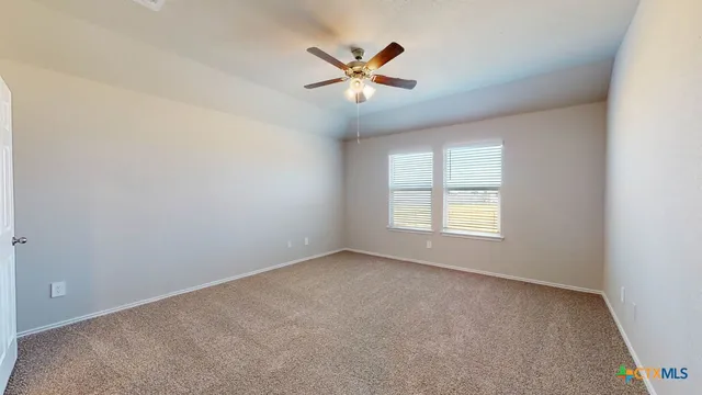 an empty room with a ceiling fan and windows