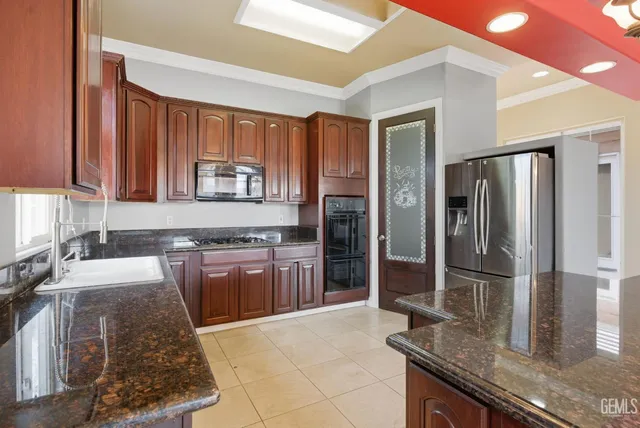 a kitchen with stainless steel appliances granite countertop a stove a sink and a microwave