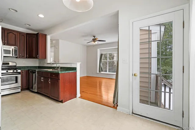 a kitchen with stainless steel appliances granite countertop a stove a sink and a refrigerator with wooden floors