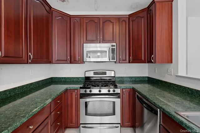 a kitchen with granite countertop wood cabinets and stainless steel appliances