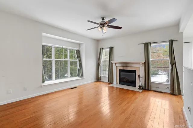a view of an empty room with wooden floor fireplace and a window