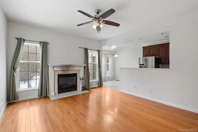 a view of a livingroom with a fireplace a ceiling fan and wooden floor