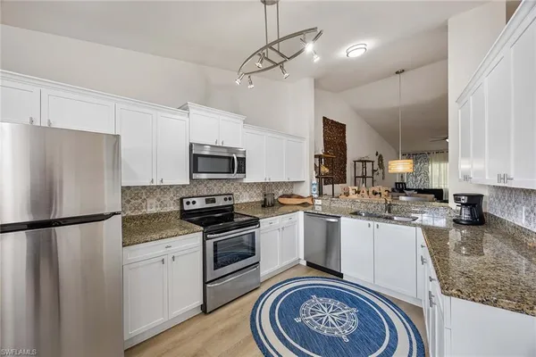 a kitchen with granite countertop stainless steel appliances a sink a counter top space cabinets and stainless steel appliances
