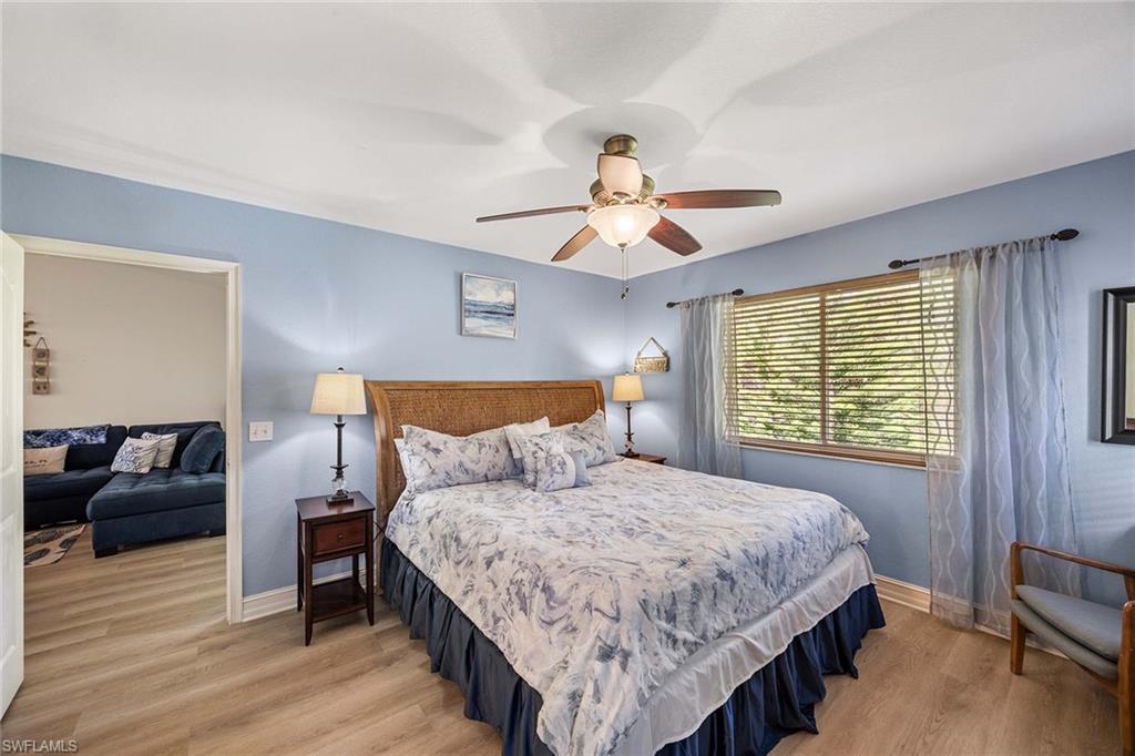 640 Luisa Lane, Unit 8044 Naples, FL 34104 - Photo 21 of 46 a bedroom with a bed and a chandelier