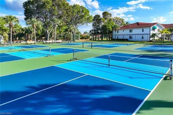 a view of a tennis ground with large trees
