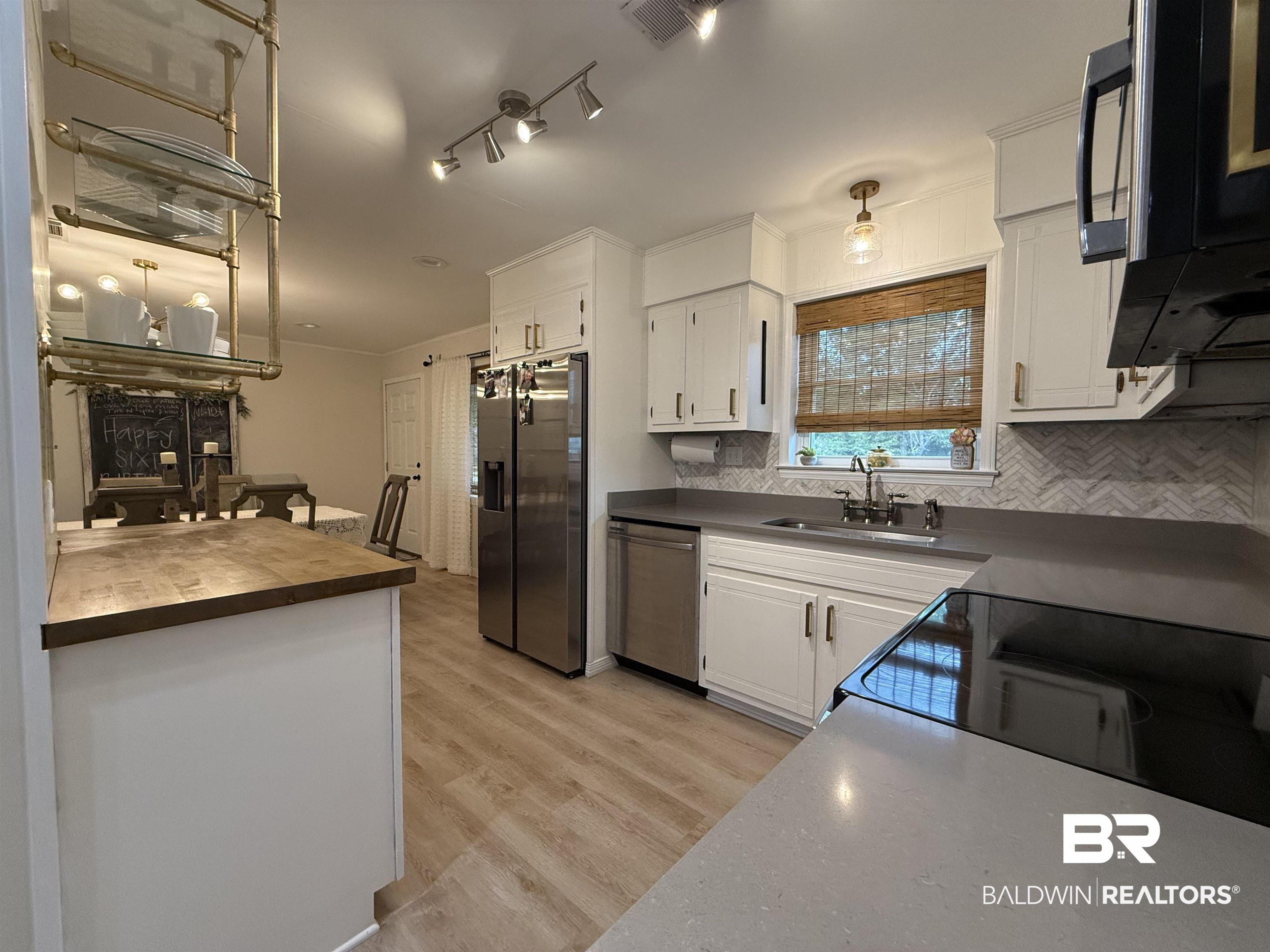 90 Florida Street Monroeville, AL 36460 - Photo 17 of 31 Kitchen with decorative backsplash, white cabinetry, light hardwood / wood-style flooring, sink, and stainless steel appliances
