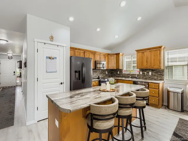 a kitchen with a refrigerator a stove a sink dishwasher with a dining table and chairs