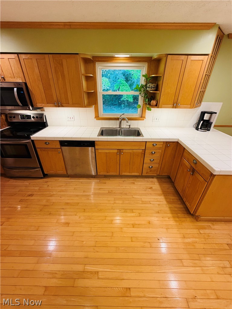 5770 Chapel Road Madison, OH 44057 - Photo 11 of 42 U-shaped kitchen with wood cabinetry, stainless steel appliances, white countertops, and wood-finish flooring