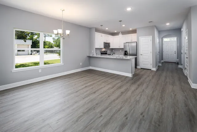 a view of kitchen with kitchen island wooden floors appliances and cabinets