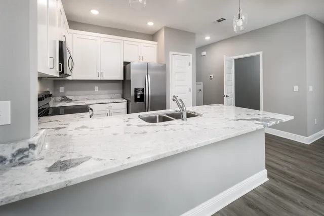 a view of a kitchen with kitchen island a sink stainless steel appliances and cabinets