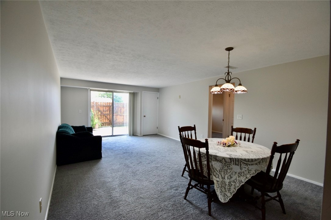 8955 West Ridge Road, Unit D Elyria, OH 44035 - Photo 20 of 33 Dining space with dark colored carpet, a chandelier, and a textured ceiling