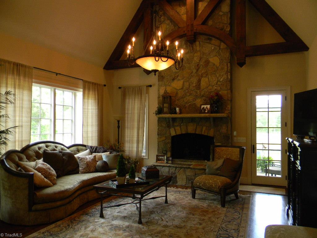 820 Pinebrook School Road Mocksville, NC 27028 - Photo 20 of 28 Great room with stone fireplace, decorative timbers, hardwood floors and access to the screened in back porch.