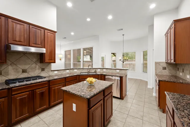 a kitchen with granite countertop stainless steel appliances a stove sink and microwave