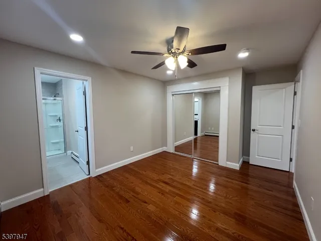 a view of empty room with wooden floor and fan