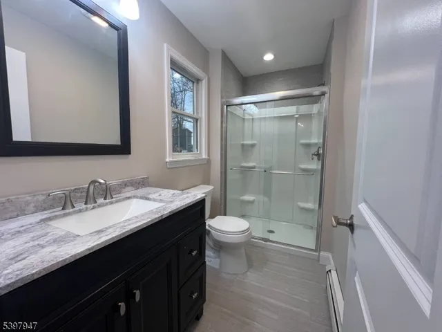 a bathroom with a granite countertop sink toilet and shower