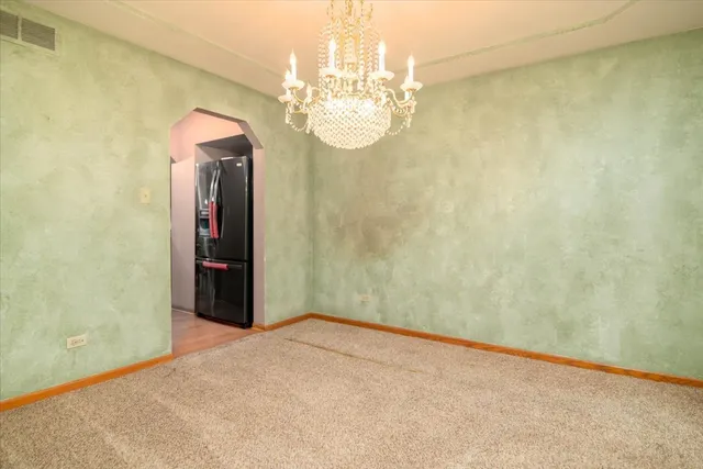 en empty room with a chandelier fan and wooden floor
