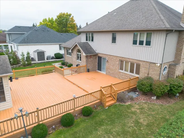 a view of a white house with a yard plants and large tree