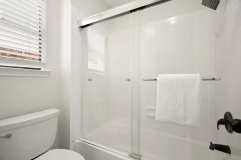 a bathroom with a granite countertop sink two mirror and a shower