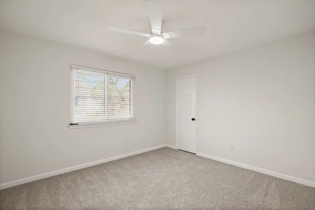 an empty room with a window and ceiling fan