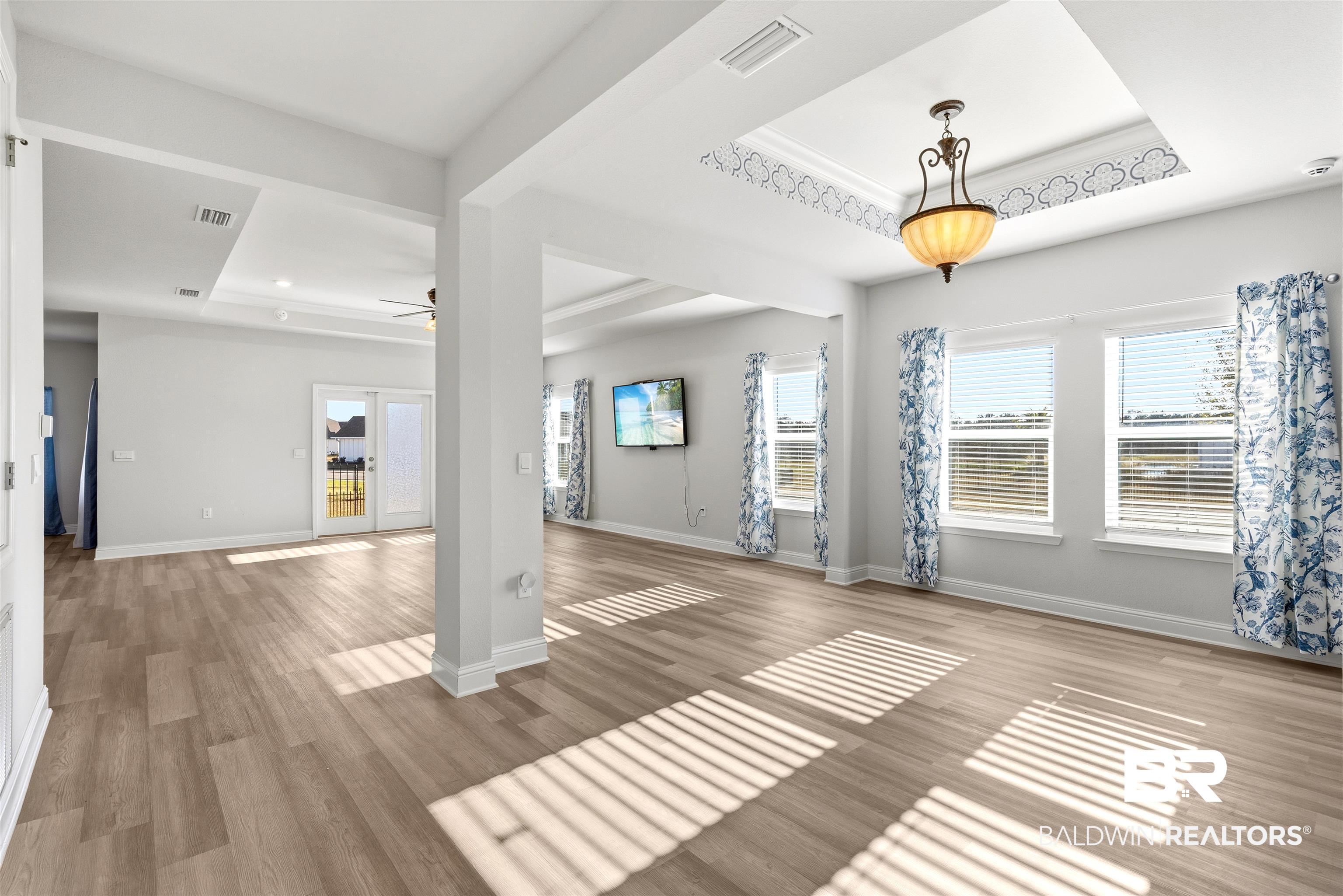 485 Shepard Street Gulf Shores, AL 36542 - Photo 9 of 53 Unfurnished living room featuring a tray ceiling, light wood-style floors, and a ceiling fan