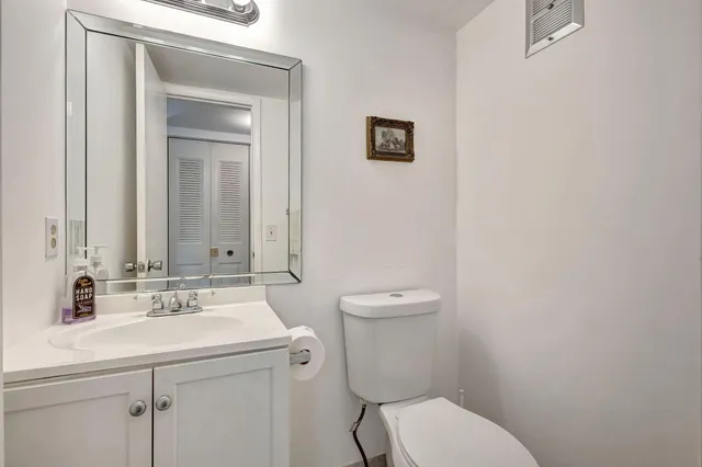 a bathroom with a toilet sink vanity and mirror