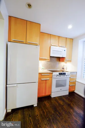 a kitchen with granite countertop wooden floors and white stainless steel appliances