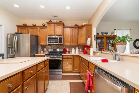 a kitchen that has a sink stainless steel appliances and white cabinets