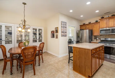 a kitchen with stainless steel appliances kitchen island granite countertop a table chairs and a refrigerator