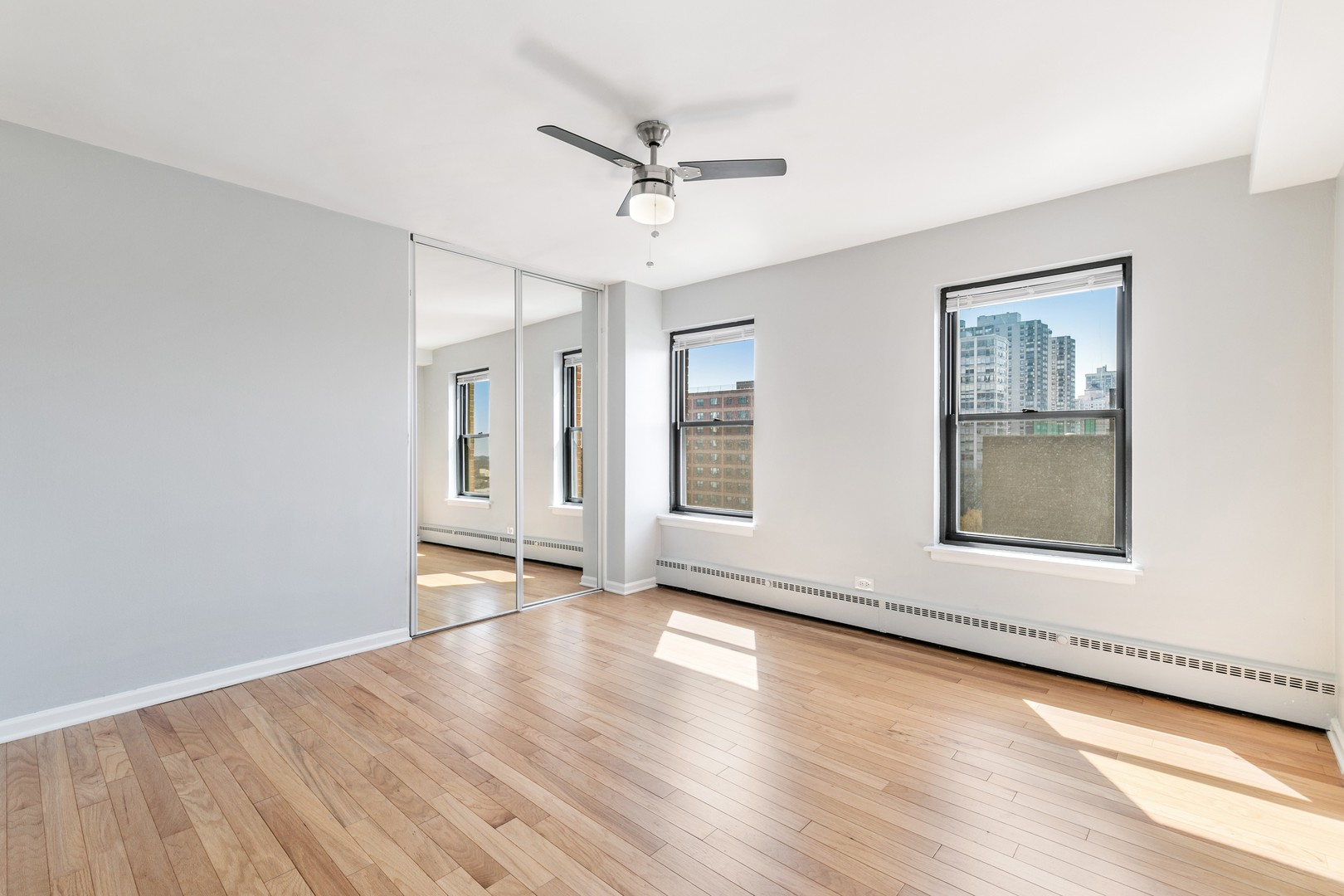 5858 North Sheridan Road, Unit 904 Chicago, IL 60660 - Photo 4 of 15 an empty room with wooden floor chandelier fan and windows
