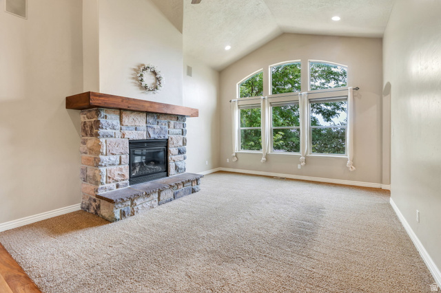 373 East Alexander Drive Elk Ridge, UT 84651 - Photo 24 of 69 Vaulted ceiling with recessed lighting, stone-clad fireplace with wood mantel, large arched window, and neutral carpeting