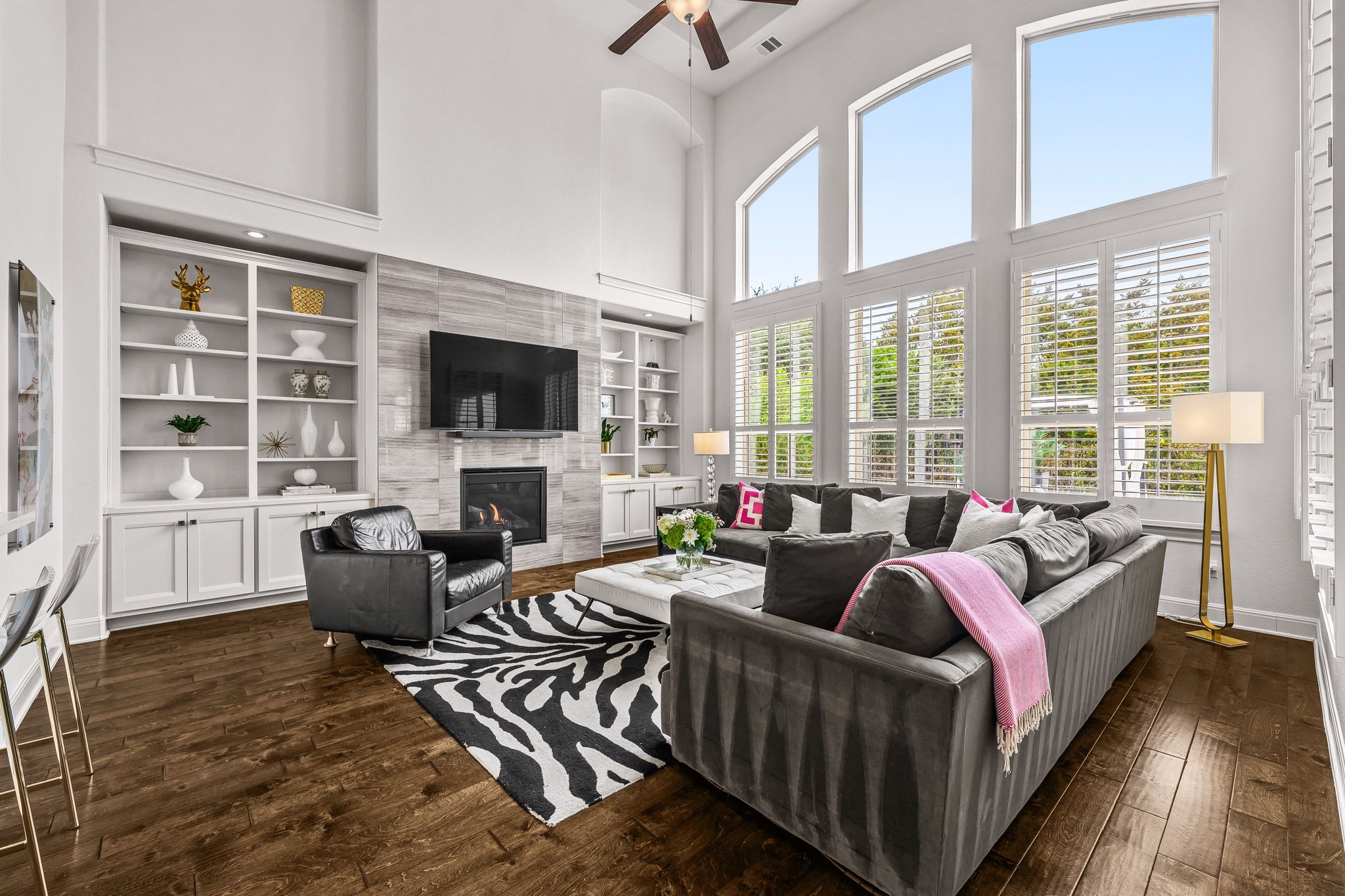 4609 Gallego Circle Austin, TX 78738 - Photo 9 of 40 Living room featuring a high ceiling, dark wood-style floors, a tiled fireplace, ceiling fan, and built in shelves