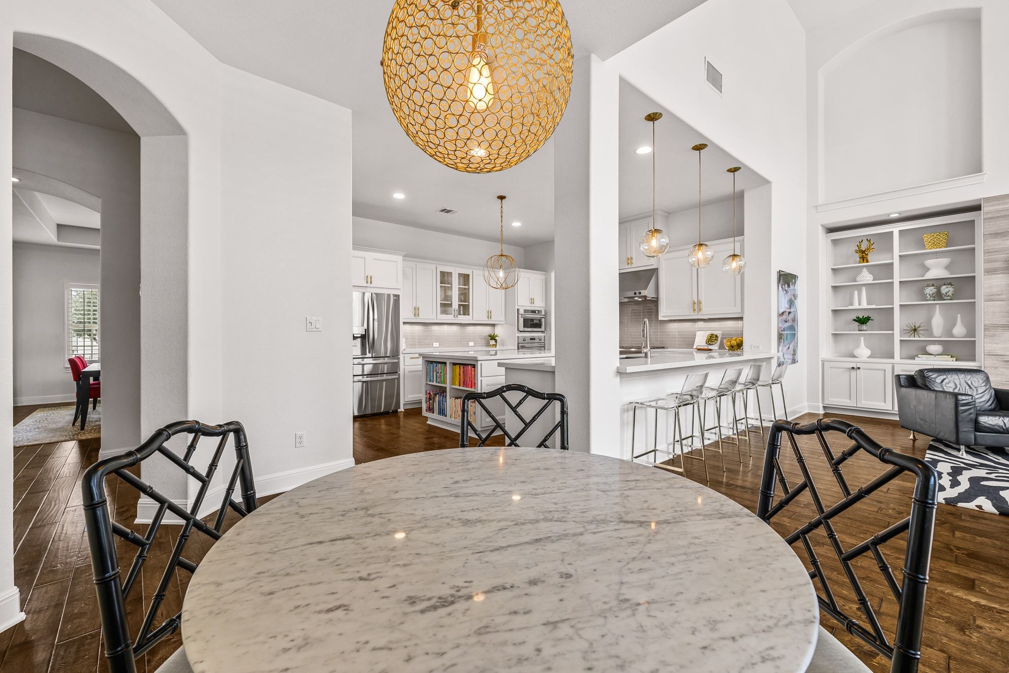4609 Gallego Circle Austin, TX 78738 - Photo 8 of 40 Breakfast area open to kitchen and family/living room, featuring arched walkways, dark wood-style flooring, built-in features, recessed lighting, and decorative lighting.