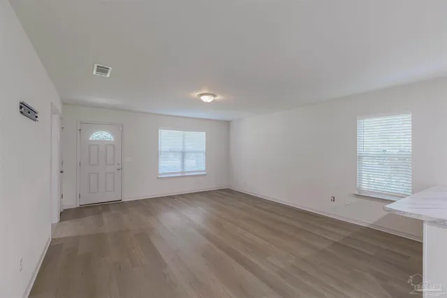 an empty room with wooden floor and windows