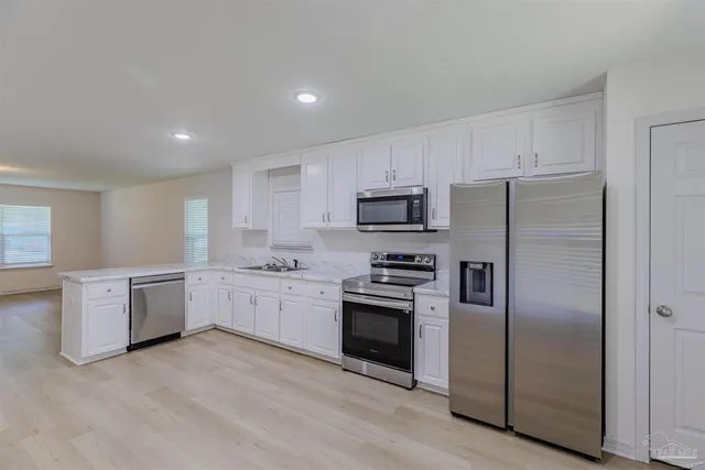 a kitchen with a refrigerator stove a sink and dishwasher with wooden floor