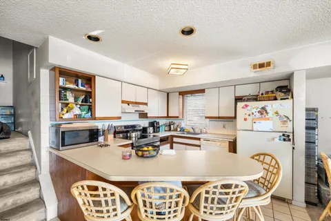 a kitchen with a dining table chairs and a refrigerator