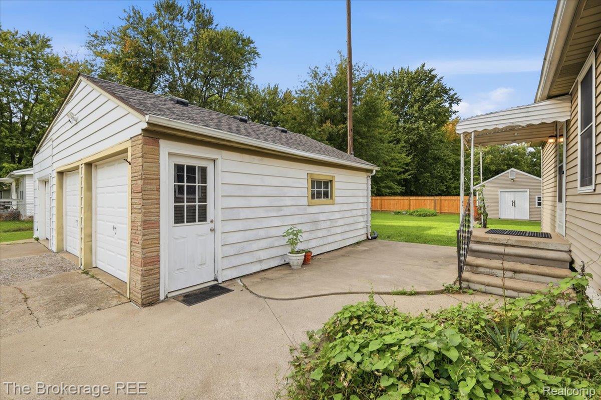 Detached two-car garage with white siding and brick accents