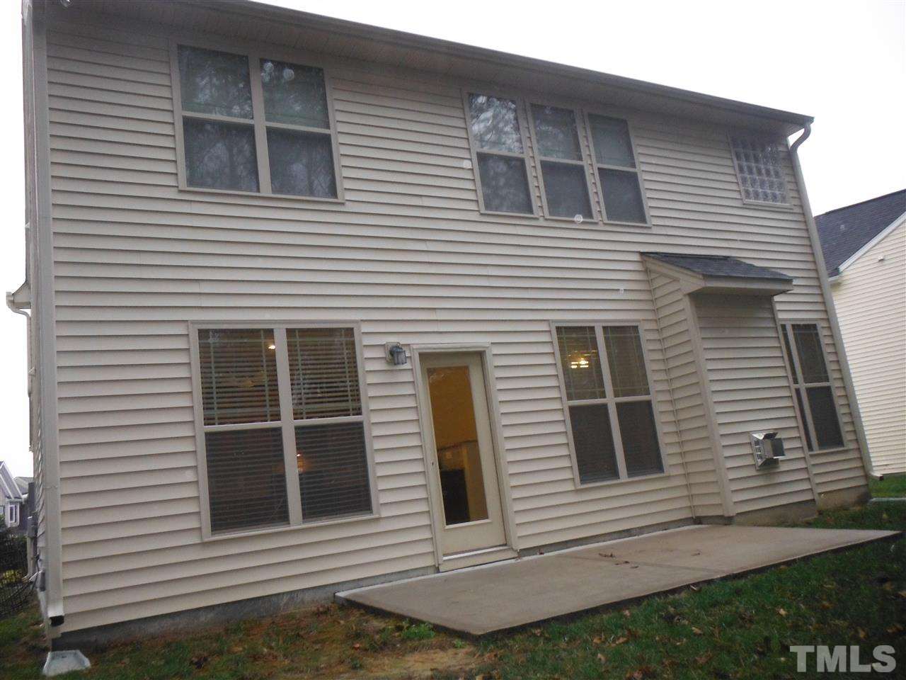 Back of home, concrete patio overlooking yard & wooded area