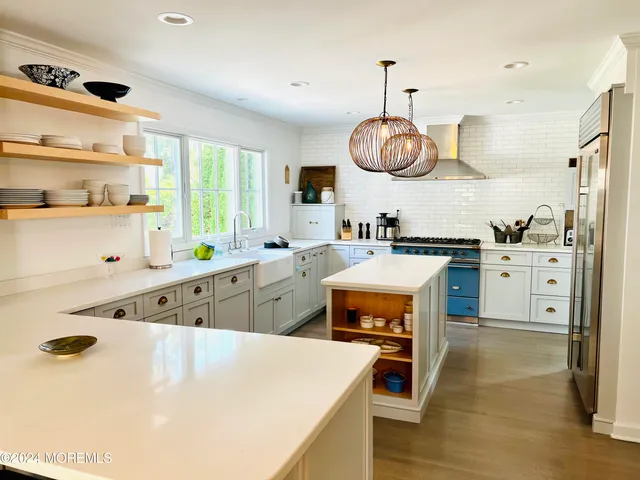 a kitchen with stainless steel appliances a sink a stove a refrigerator cabinets and a window