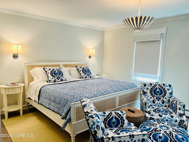 a bed sitting in a bedroom next to a window and a chandelier