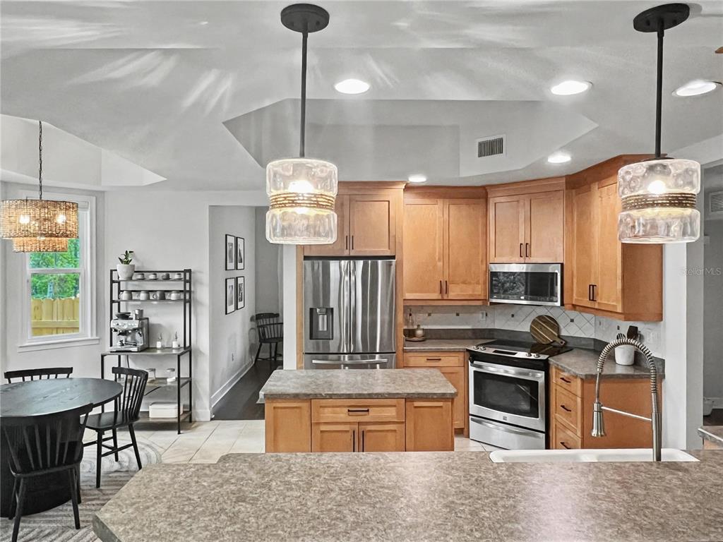 12912 Southwest 3rd Place Newberry, FL 32669 - Photo 4 of 38 a kitchen with stainless steel appliances granite countertop a stove a refrigerator a oven a sink with a dining table and chairs