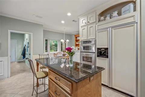 a kitchen with stainless steel appliances granite countertop a dining table chairs and granite counter tops