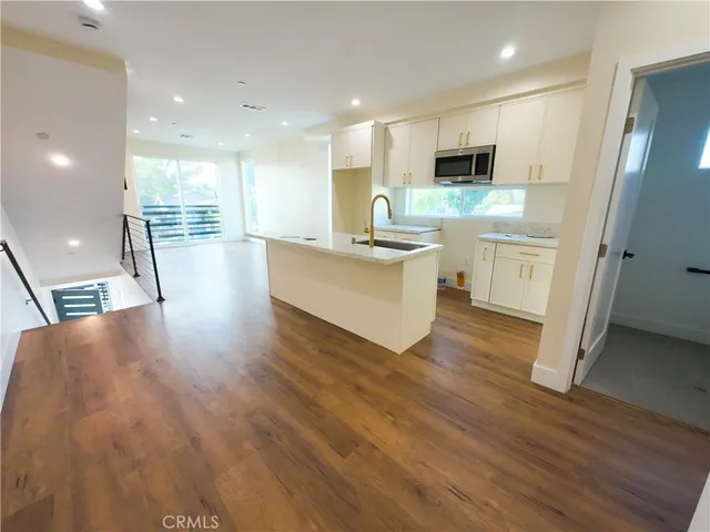 a view of a kitchen with kitchen island a sink wooden floor and a counter top space