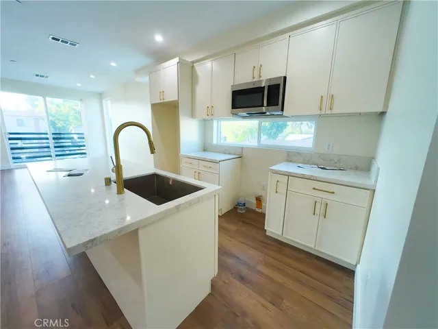 a kitchen with stainless steel appliances a sink a stove a microwave a sink a refrigerator and cabinets