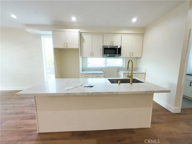 a kitchen with kitchen island a sink and a stove top oven with wooden floor