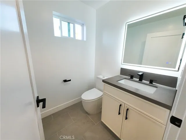a bathroom with a granite countertop toilet sink and mirror
